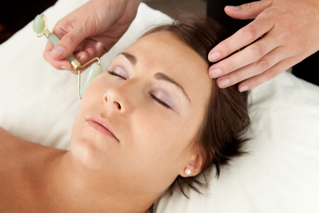female receiving gua sha facial with jade roller
